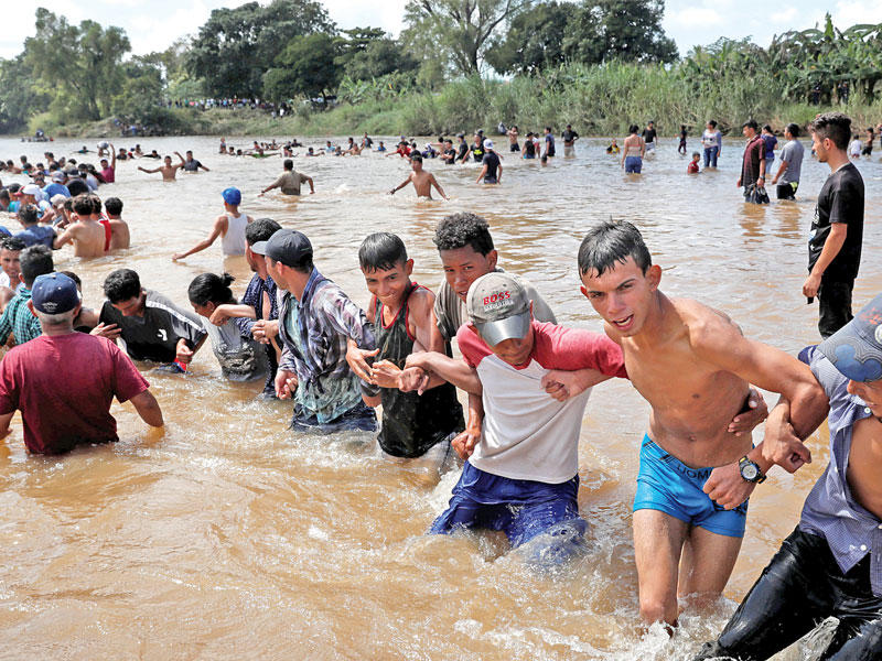 مهاجرون يحاولون عبور نهراً حدودياً بين غواتيمالا والمكسيك في طريقهم الى أميركا (رويترز)