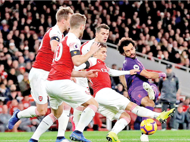 صلاح نجم ليفربول في محاولة لاستخلاص الكرة من لاعبي أرسنال