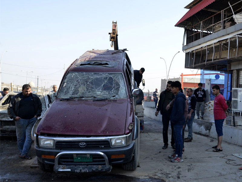 العراقيون يقفون في موقع هجوم سيارة مفخخة انفجر في اليوم السابق في الموصل