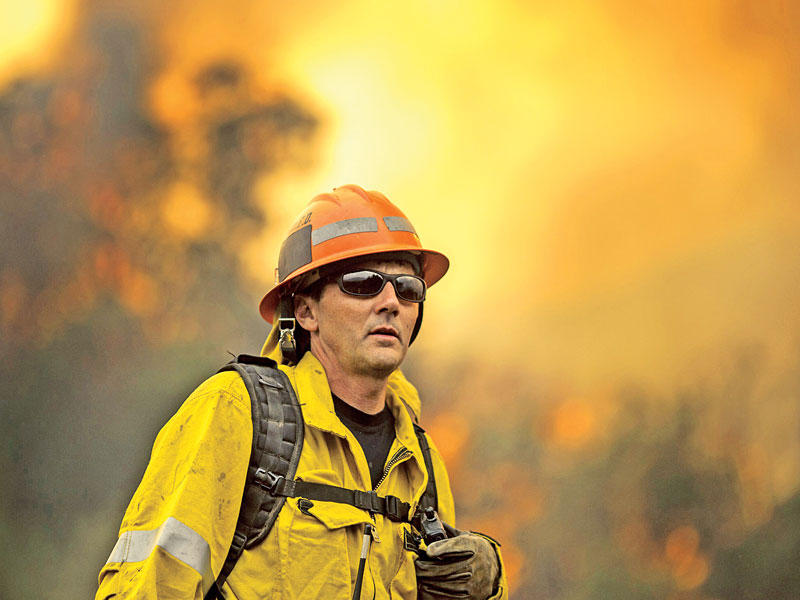 رجل إطفاء يشارك أمس الأول في عملية إخماد النيران بإحدى غابات كاليفورنيا (أ ف ب)