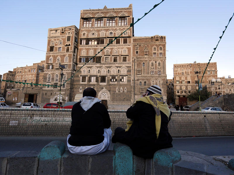 يمنيان يجلسان على الأرض في أحد أحياء مدينة صنعاء القديمة (اي بي آي)
