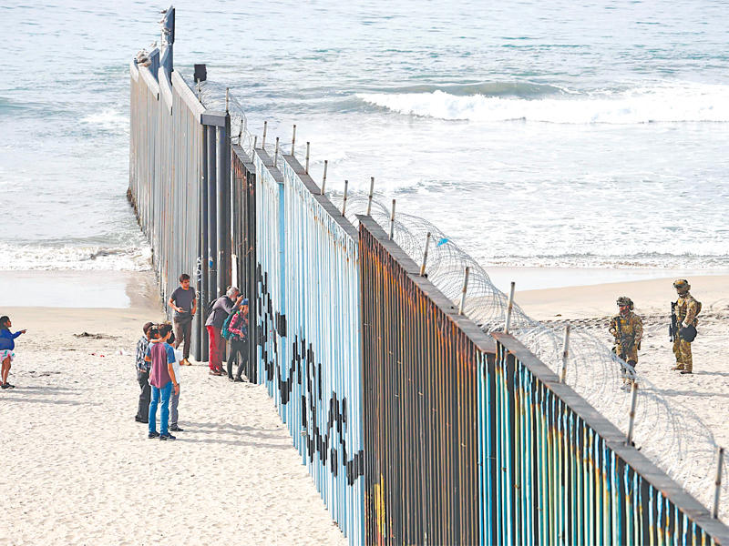 مكسيكيون يتحدثون مع جنود أميركيين عبر السياج الحدودي في بلاييس دو تيوانا أمس الأول (أ ف ب) 