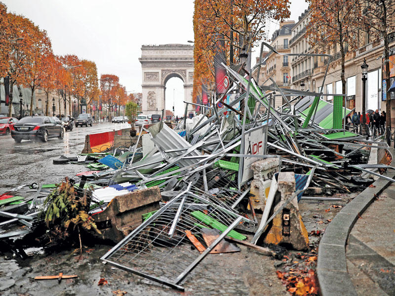 إزالة حواجز حديدية استخدمها محتجو «السترات الصفراء» في جادة الشانزليزيه أمس الأول (رويترز)
