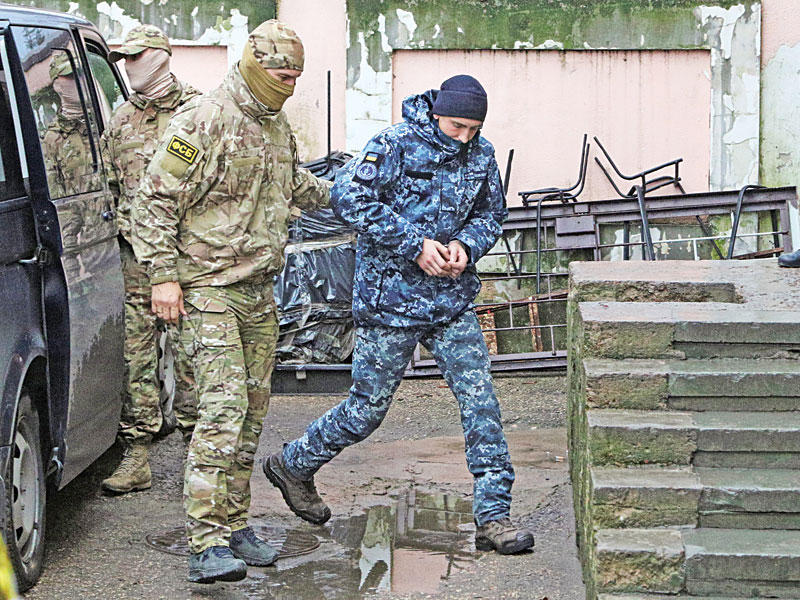 جندي روسي يقتاد بحاراً أوكرانياً مكبّل اليدين للمثول أمام المحكمة في سيمفيروبول بالقرم أمسtt (رويترز)