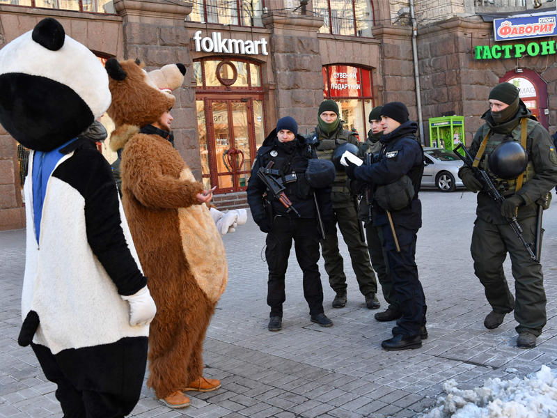 عناصر من الحرس الوطني الأوكراني يتحدثون مع رجلين متنكرين بزي دببة في كييف أمس    (أ ف ب)
