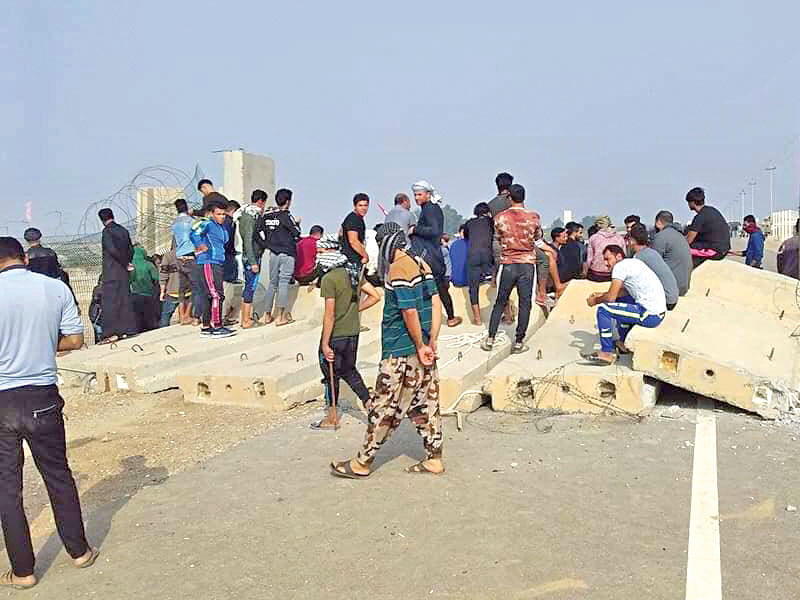 متظاهرون يزيلون جدراناً كونكريتية على مدخل «حقل القرنة 2» أمس 