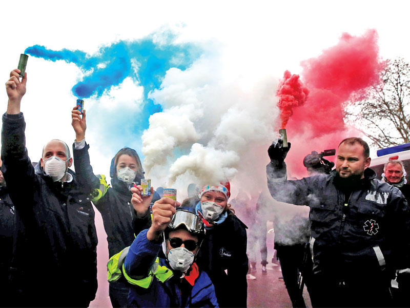 سائقو سيارات الإسعاف يرسمون بالدخان الملوّن العلم الفرنسي خلال وقفة احتجاجية لهم في ساحة الكونكورد بباريس أمس (رويترز)