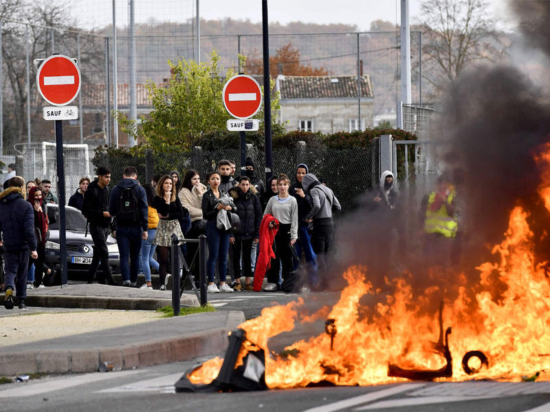 طلاب أمام إطارات مشتعلة احتجاجاً على قرار الحكومة رفع الأسعار على التعليم في بوردو أمس  (ا ف ب)