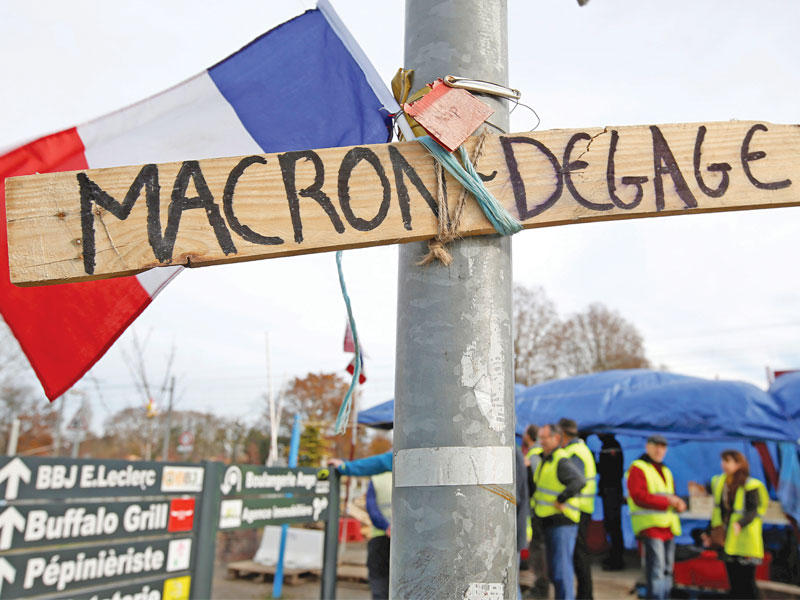 عدد من «السترات الصفراء» يقفلون أحد الشوارع بعد تعليقهم خشبة كتب عليها «ماكرون ارحل» في بوردو  أمس (رويترز)