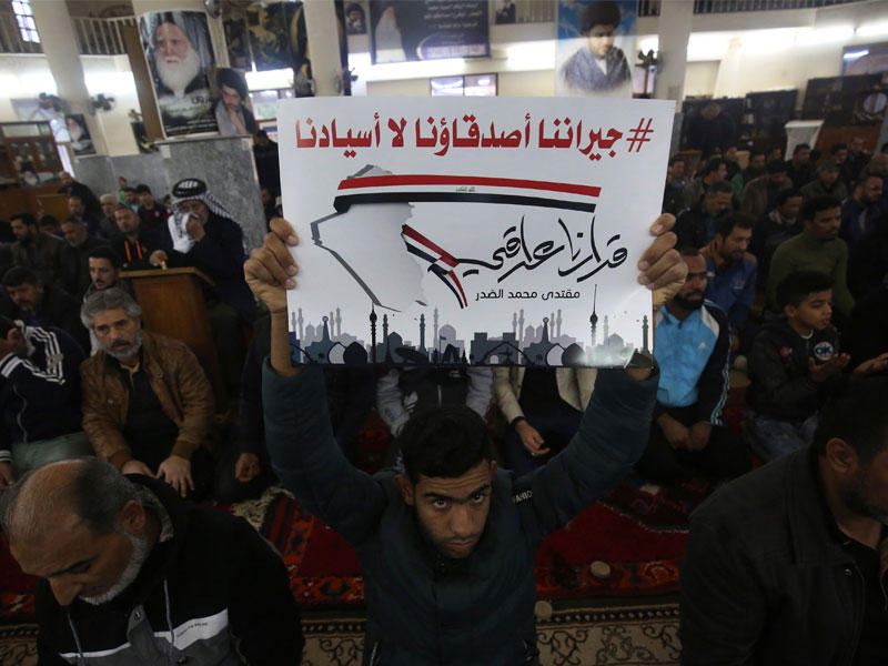 عراقي يرفع أمس لافتة خلال صلاة بمسجد في مدينة الصدر كتب عليها «جيراننا أصدقاؤنا لا أسيادنا قرارنا عراقي» وهو الشعار الذي رفعه نواب الصدر خلال جلسة البرلمان الفاشلة (أ ف ب)