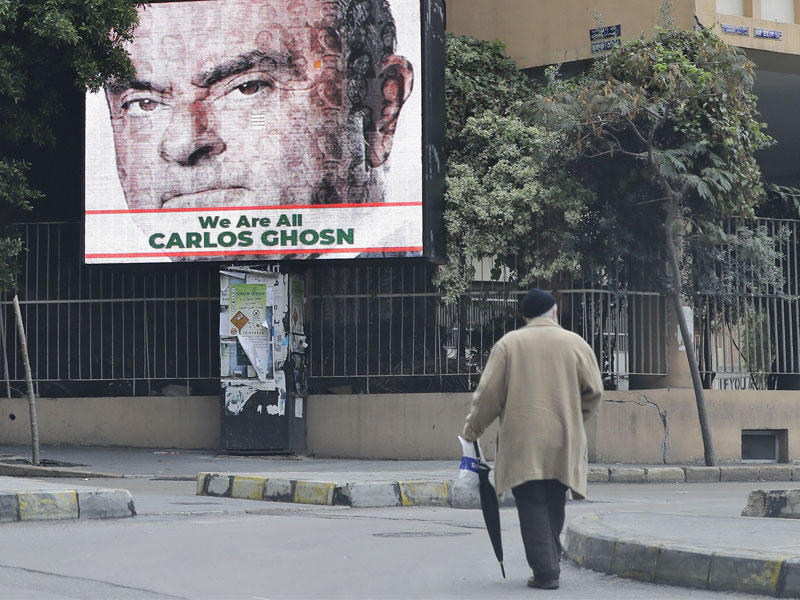رجل يمر قرب لوحة إعلانية كبيرة تحمل صورة كارلوس غصن في بيروت أمس             (ا ف ب)