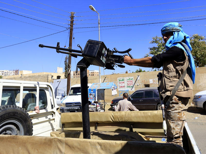 جندي يمني يقف وراء مدفع رشاش في سيارة في شارع خارج مكاتب الأمم المتحدة خلال مسيرة مناهضة للحرب في صنعاء