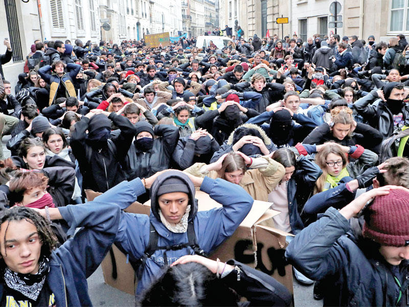 طلاب ثانوية يركعون على الأرض وأيديهم خلف رؤوسهم خلال تظاهرة احتجاجية على الاصلاحات الحكومية في باريس أمس  (رويترز)