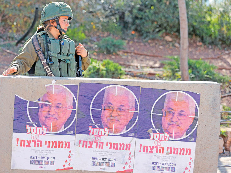 ملصقات تدعو إلى قتل الرئيس الفلسطيني على أحد الحواجز الإسرائيلية قرب مستوطنة ميغرون بالضفة أمس (أ ف ب)