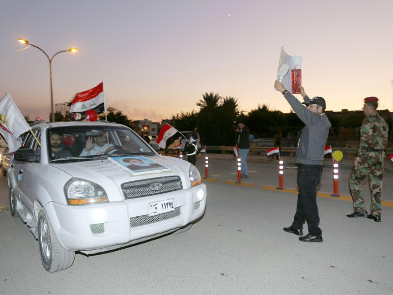 يحمل العراقيون العلم الوطني العراقي وهم يدخلون المنطقة الخضراء شديدة التحصين لإحياء ذكرى الانتصار على تنظيم  (داعش)