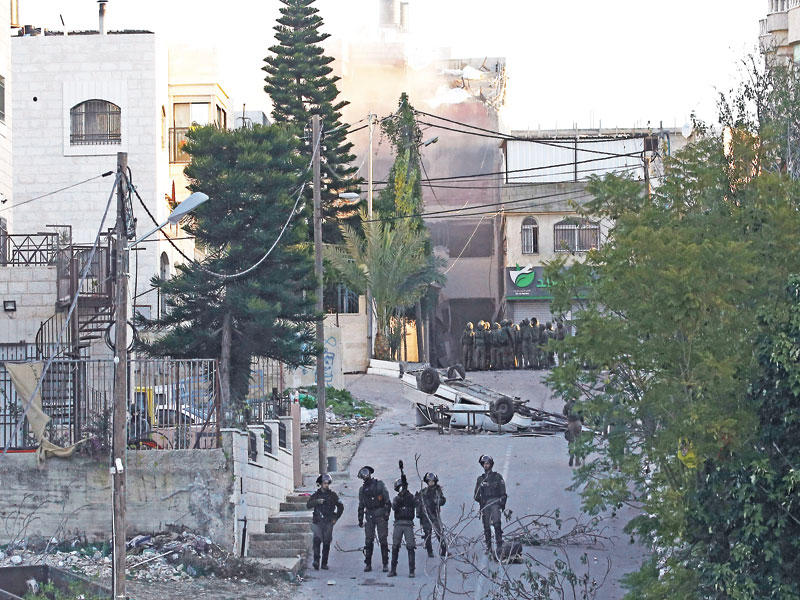 قوات إسرائيلية تغلق شارعا خلال هدمها لمنزل أسرة فلسطيني متهم بقتل جندي في رام الله أمس (أ ف ب)