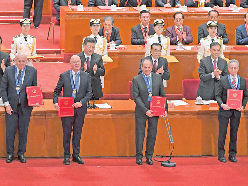 الرئيس الصيني مصفقاً لبعض الشخصيات الأجنبية التي منحها ميداليات في ختام كلمته ببكين أمس (أ ف ب)