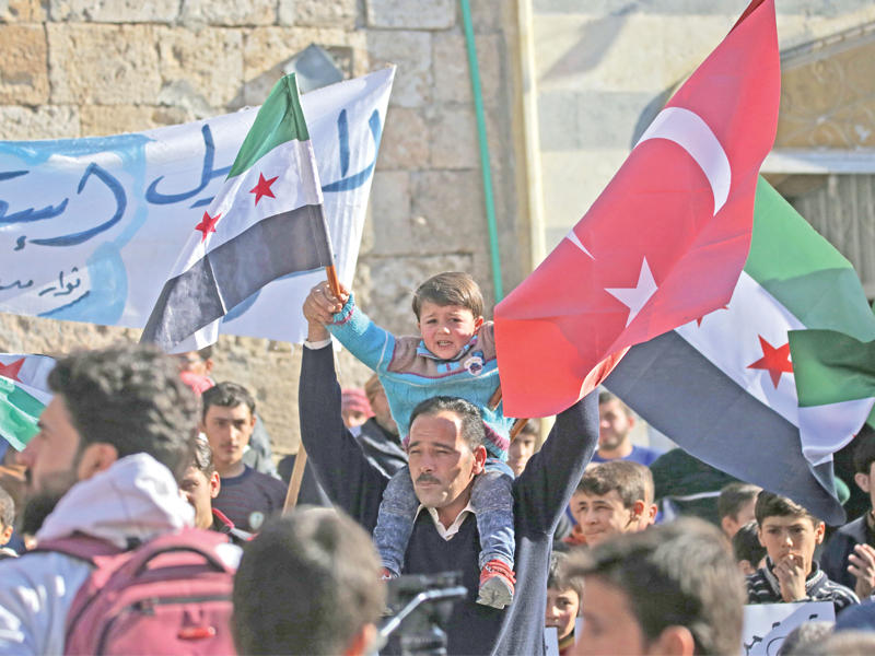 سوريون يلوحون بأعلام تركيا والمعارضة خلال تظاهرة دعم لأنقرة شمال حلب أمس (أ ف ب)