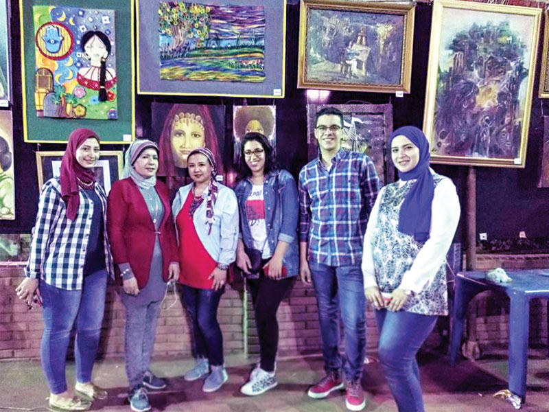 فنانون أمام لوحاتهم في معرض المنصورة