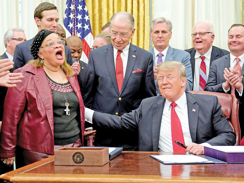 ترامب ممسكاً بذراع حفيدة مارتن لوثر كينغ خلال تأديتها أغنية في البيت الأبيض أمس الأول (رويترز)