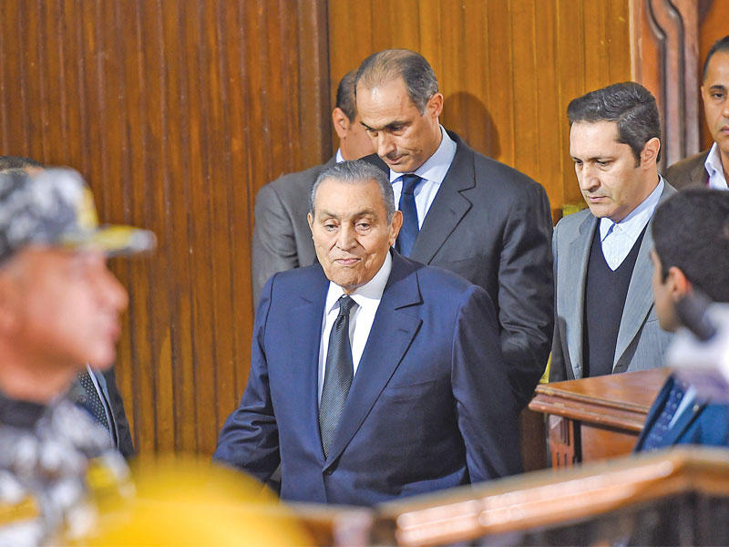 مبارك لدى دخوله قاعة المحكمة مع نجليه علاء وجمال في جنوب القاهرة أمس      (أ ف ب) 