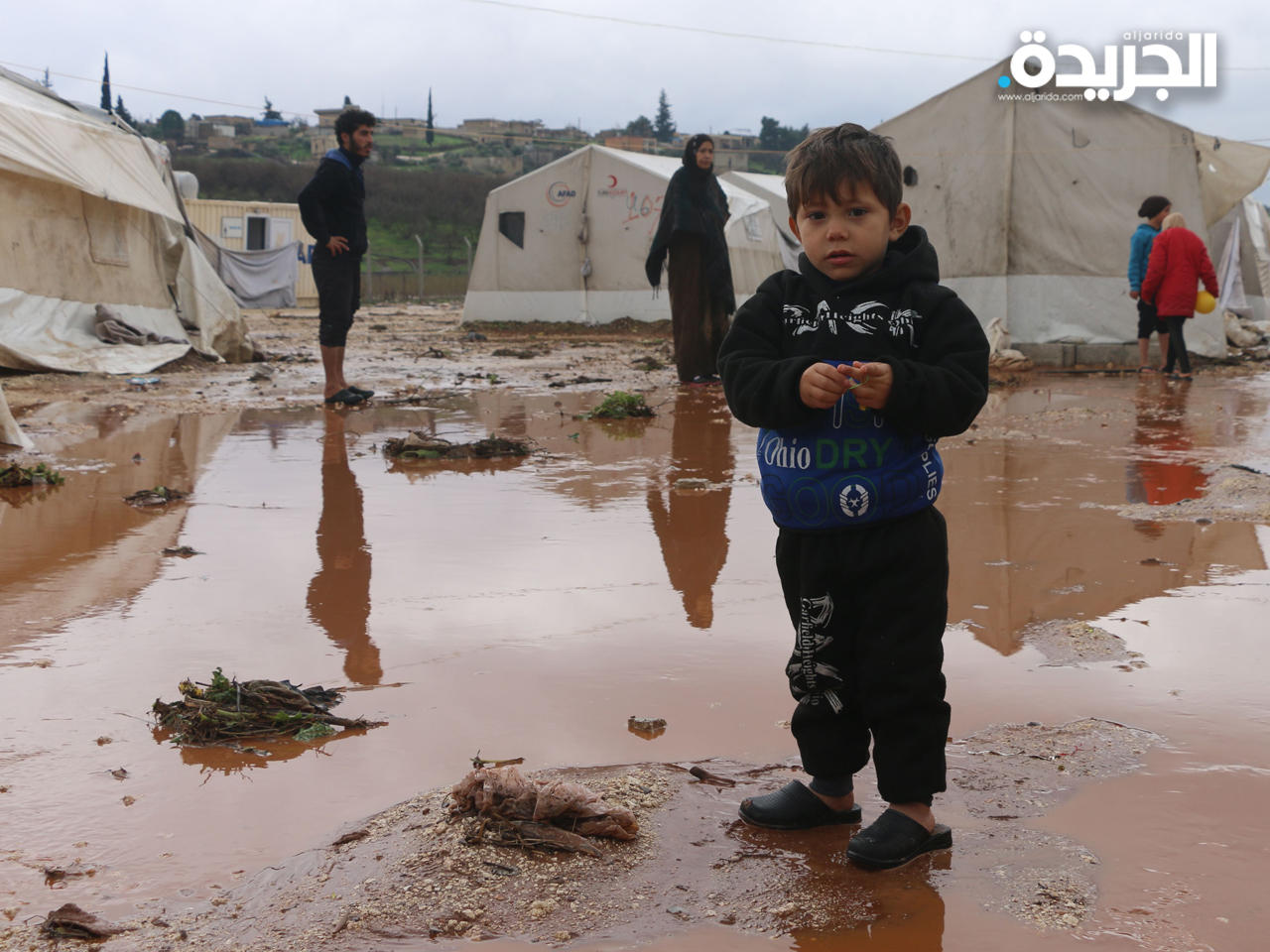 طفل سوري يقف في برك المياه بمخيم دير البلوت للاجئين في ريف عفرين