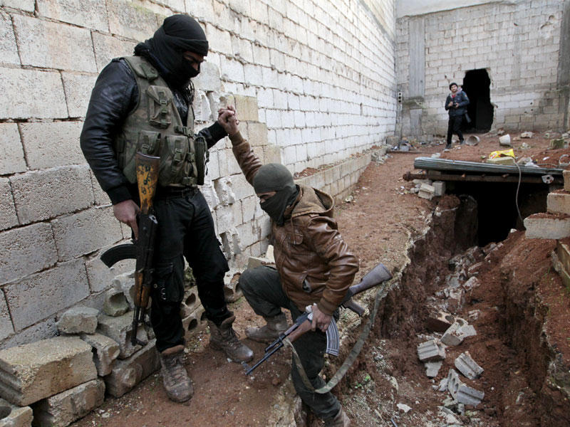 مقاتل مدعوم من تركيا يساعد زميله على الخروج من نفق في بلدة تادف بحلب يوم الخميس (رويترز)