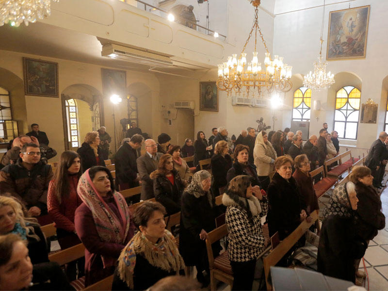 سوريون يؤدّون صلاة الميلاد بالكنيسة الأرثوذكسية في دمشق أمس (إي بي إيه)