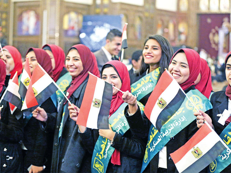 نساء يحملن أعلاماً مصرية داخل كاتدرائية الميلاد في العاصمة الإدارية أمس الأول (إي بي ايه)