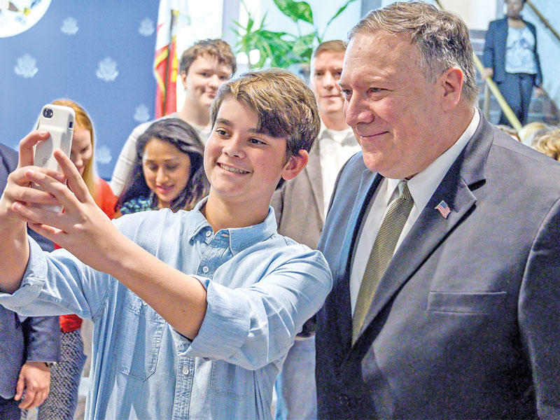 أحد أبناء العاملين في السفارة الأميركية لدى المنامة يلتقط صورة مع بومبيو خلال تفقده السفارة أمس الأول (رويترز)