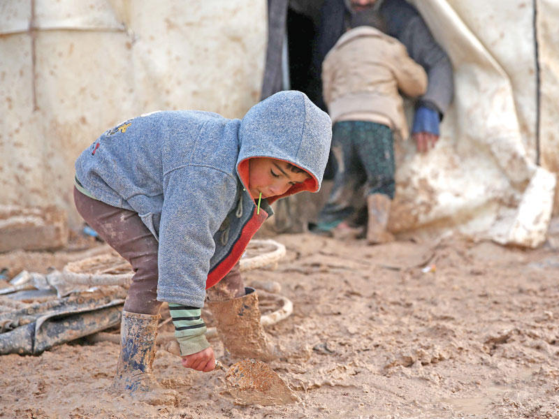 صبي سوري يمهد الطين أمام خيمة أسرته قرب قرية شمارين شمال حلب أمس الأول (أ ف ب)