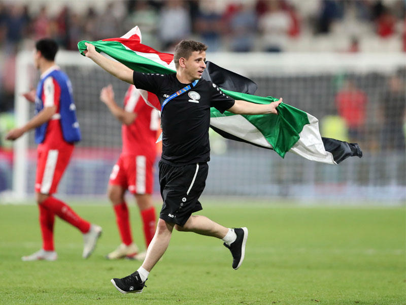 عضو في هيئة تدريب فلسطين حاملاً علم بلاده بعد المباراة  (رويترز) 