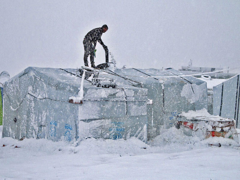 لاجئ سوري في مخيم للاجئين بوادي البقاع يحاول إزالة الثلج عن خيمته أمس الأول t(أ ف ب)