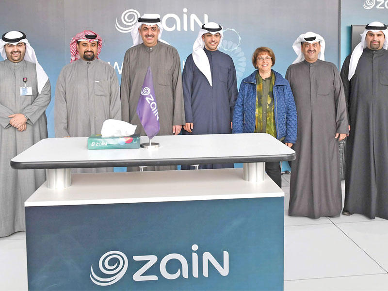 الجري يتوسط الخشتي وفريق «زين» في جناح الشركة بالمعرض