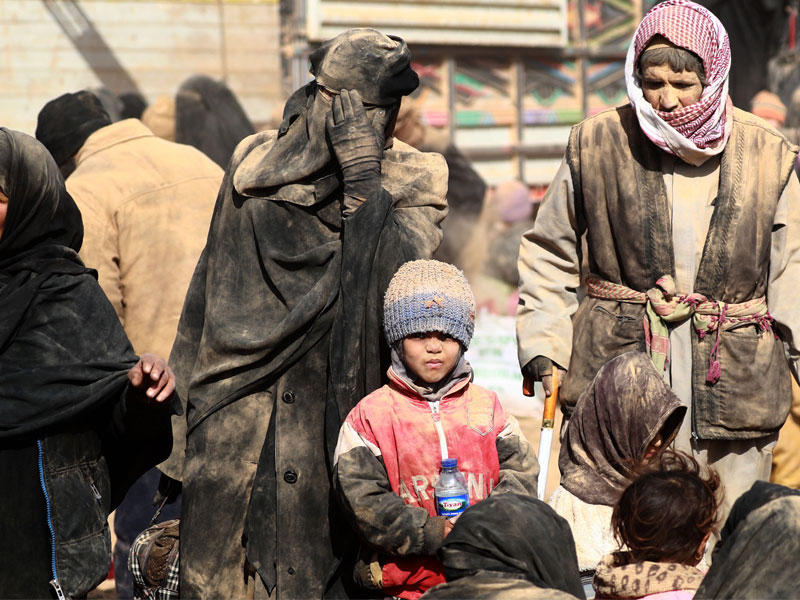 سوريون فارون من معارك دير الزور قرب الحدود مع العراق يصلون مغبرين بتراب الصحراء إلى مناطق سيطرة الأكراد (أ ف ب)