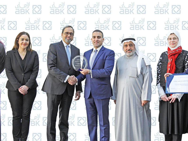 سومناث مينون يتسلم الجائزة من شريف عبدالسلام  ورنا أبو حسن بحضور مجموعة من موظفي البنك