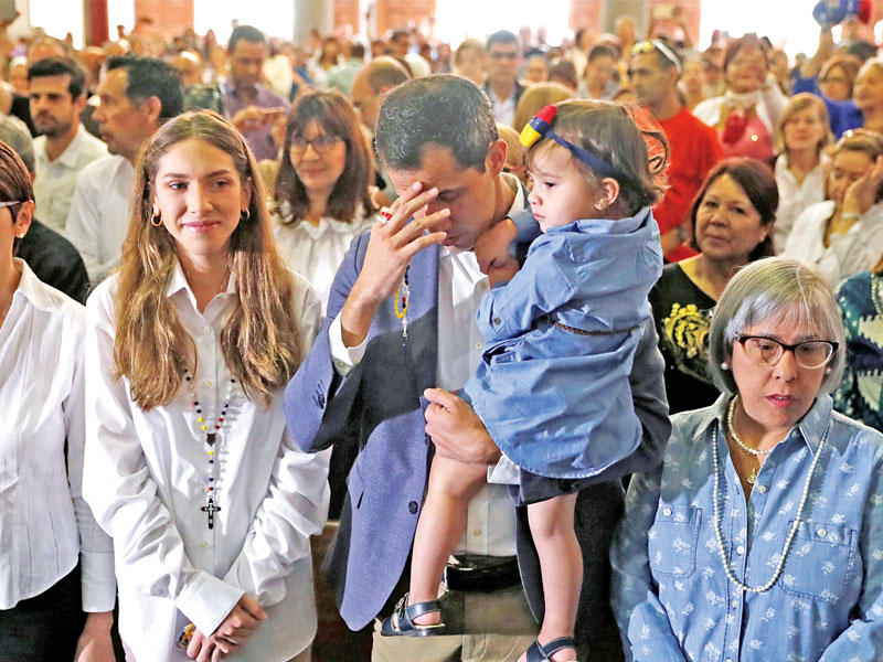 غوايدو حاملاً ابنته وإلى جانبه زوجته خلال قداس في كراكاس أمس الأول    (رويترز)