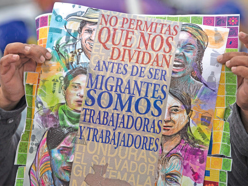 مهاجر يرفع لافتة رسم عليها أشخاص من جنسيات مختلفة خلال تظاهرة قرب الكابيتول أمس الأول للمطالبة بتفعيل قانون يسمح للمهاجرين بالعيش والعمل في أميركاt  (اي بي ايه)