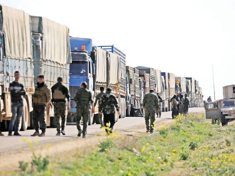 مقاتلو «قسد» مع قافلة شاحنات على مشارف قرية الباغوز أمس الأول (رويترز)