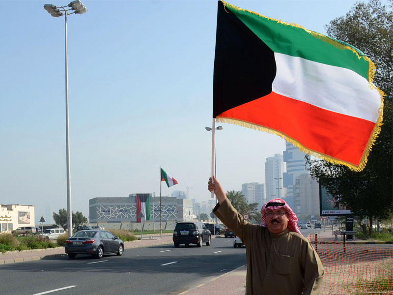 عجوز يتكئ على عصاه ويرفع العلم باليد الأخرى