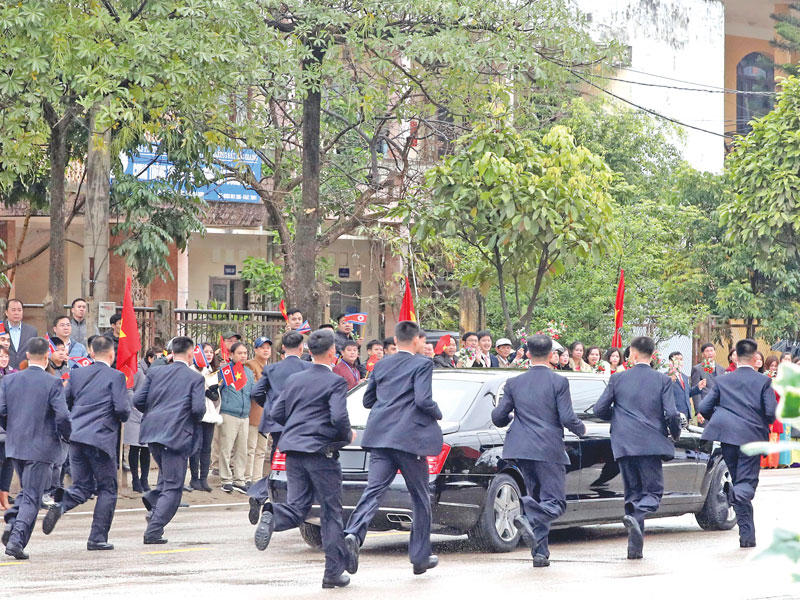حراس زعيم كوريا الشمالية يلحقون بسيارته بعد وصوله إلى هانوي أمس (رويترز)