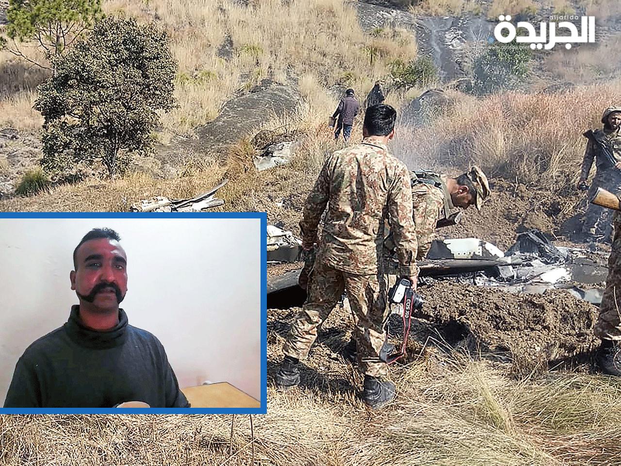 جنود باكستانيون يعاينون حطام الطائرة وفي الإطار الطيار الهندي المحتجز (ا ف ب)