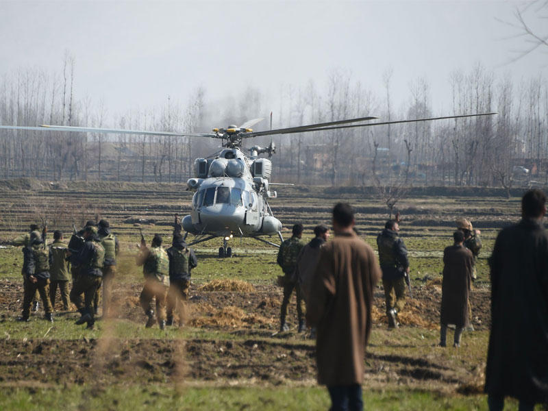 يقف الجنود بالقرب من طائرة هليكوبتر تابعة للجيش الهندي هبطت بالقرب من موقع تحطمت فيه طائرة هليكوبتر تابعة للقوات الجوية الهندية