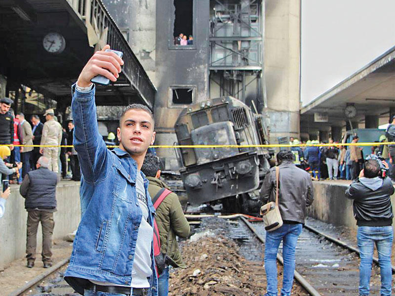 أثار شاب مصري التقط سيلفي، وهو يبتسم أمام القطار المنكوب في محطة مصر، غضباً على مواقع التواصل. واعتبر المعلقون الصورة استفزازية لمشاعر أهالي الضحايا، مطالبين بمحاسبته. nوفي تصريحات إعلامية، دافع الشاب الذي يدعى ياسر عن نفسه، مؤكداً أنه لم يكن يعرف ما حصل في المحطة وأنه التقط الصورة ليثبت لوالده أنه بخير في موقع الحادث.nمن ناحيته، اشتكى المصور الصحافي أشرف العمدة، الذي التقط صورة صاحب السيلفي، تعرضه لتهديدات بالخطف والقتل، من أسرة وأصدقاء الشاب.