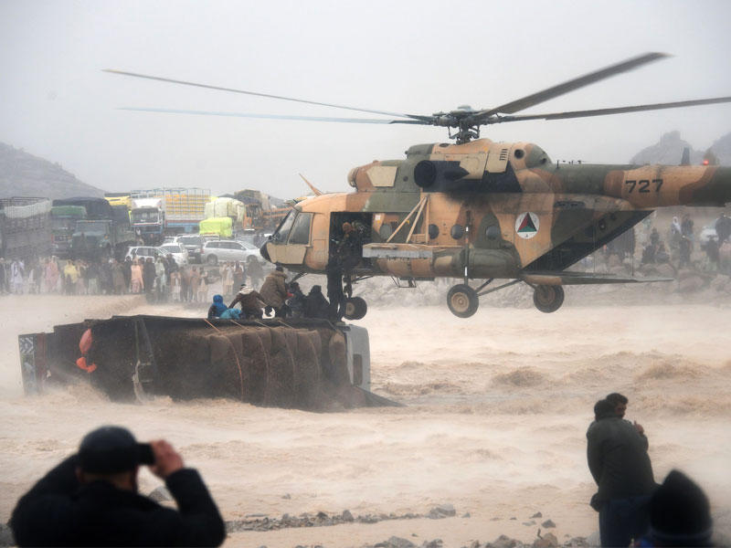 تقوم طائرة هليكوبتر عسكرية أفغانية بإنقاذ الناس من فوق شاحنة مقلوبة في منطقة تغمرها الفيضانات