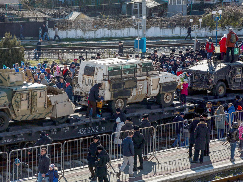 روس يلتقطون صوراً قرب آليات عسكرية بينها عربات أميركية وأخرى للأمم المتحدة غنمتها القوات الروسية من المعارضة السورية لدى وصول القطار الذي يقلها إلى القرم أمس (أ ف ب)n