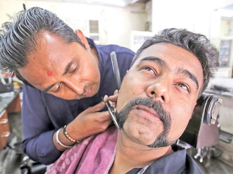 هندي يحصل من حلاّقه في مدينة أحمد آباد ، أمس، على شارب مماثل لشارب الطيار الهندي الذي أسرته باكستان أياماً (رويترز)