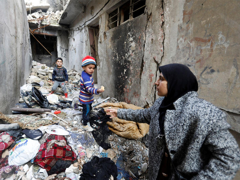 عراقية تطعم طفليها قرب منزلها المدمر في الموصل (رويترز)