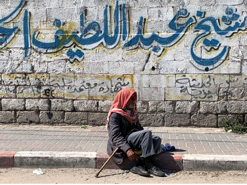رجل فلسطيني يجلس على رصيف  في مدينة غزة