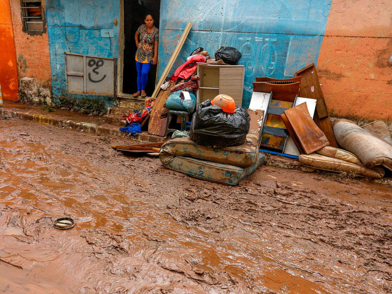 امرأة تنظر إلى ممتلكاتها المغطاة بالطين خارج منزلها بسبب الأمطار الغزيرة في أحد شوارع ساو باولو بالبرازيل